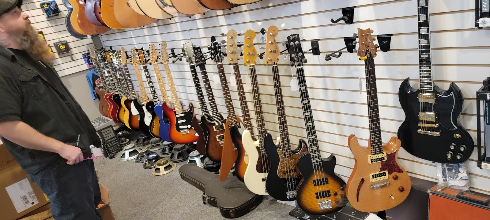 Inside The Guitar Man music store in Salisbury, MD — a full wall of electric guitars and basses on the slatwall